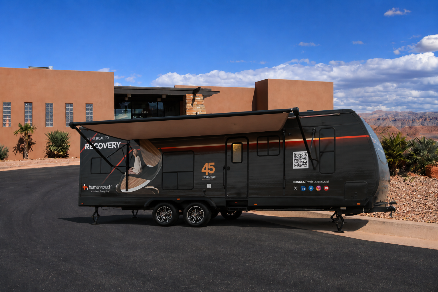 The Human Touch Recovery Lounge trailer parked in a desert golf course parking lot with awning extended